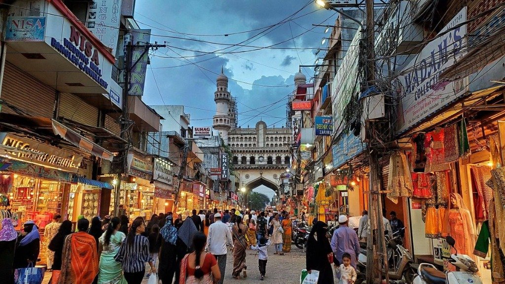 Bustling evening in Laad Bazaar with illuminated bangle shops and Charminar in the background